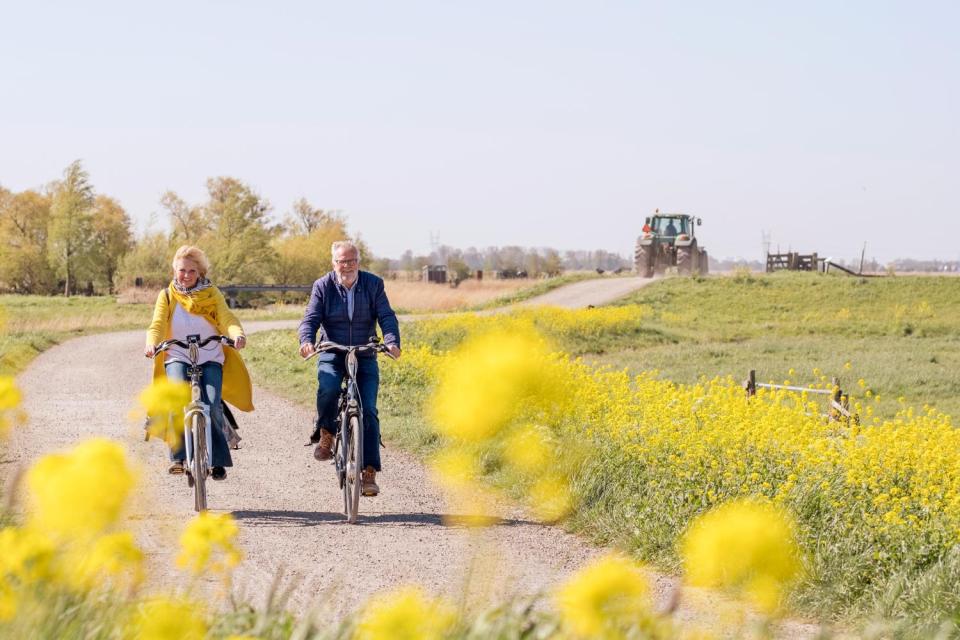 fietsers fietsend over een fietspad met een trekker op de achtergrond